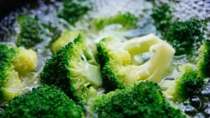 Broccoli in cottura con una fetta di pane imbevuta di aceto sul coperchio per evitare odori sgradevoli.